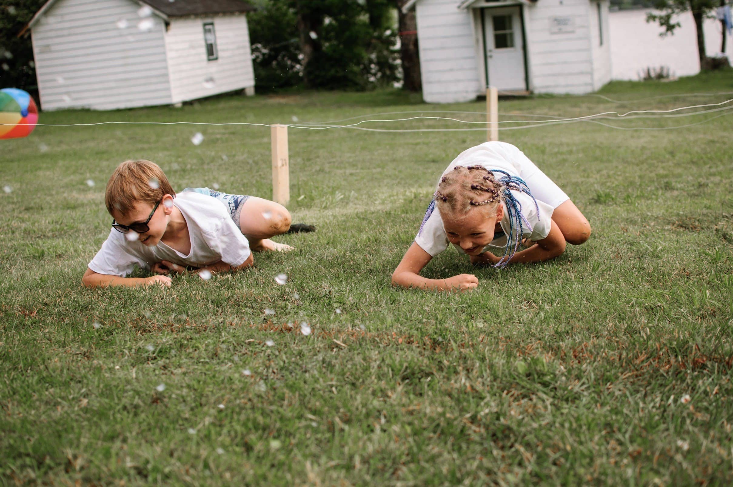A boy and girl trying not to be touched by the upper fence while climbing on the ground